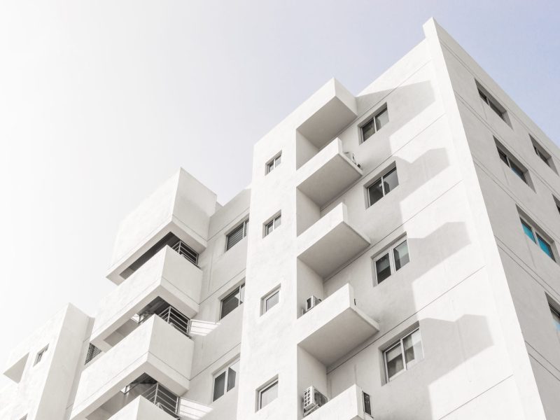 A low angle shot of a facade of a white modern building under a blue clear sky
